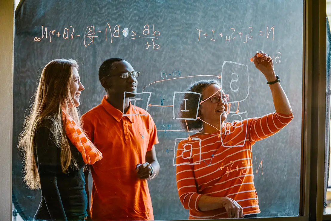 Suzanne Lenhart, a Chancellor’s Professor and the James R. Cox Professor of Mathematics, writes math problems on a clear board with students on February 09, 2018. Photo by University of Tennessee-Knoxville.